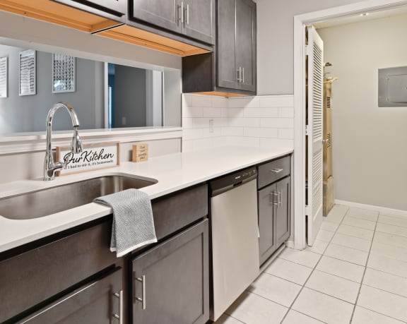 a kitchen with stainless steel appliances and white countertops and a door to a hallway