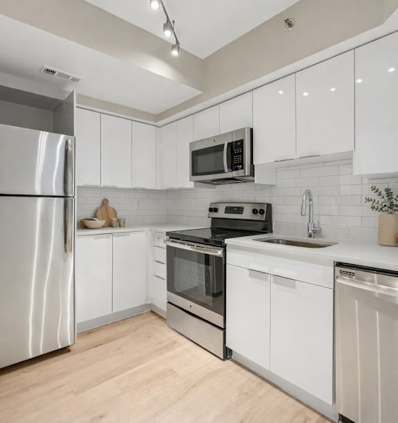 A modern kitchen with white cabinets and stainless steel appliances.