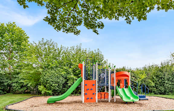 A playground with a green slide and orange and green slides.