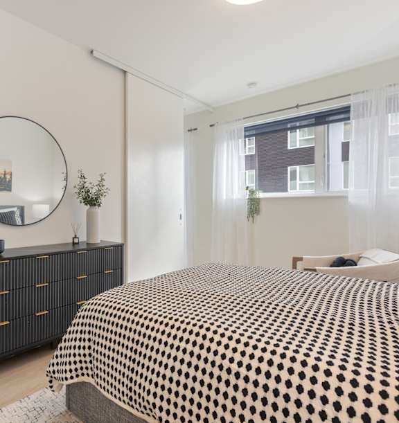 A bedroom with a bed, nightstand, and lamp.