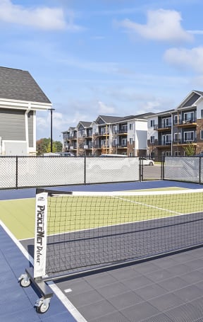 an outdoor tennis court with apartments in the background