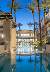 A swimming pool in a residential area surrounded by palm trees.