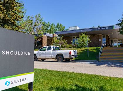 A Shouldice sign is in front of a building with a car parked in front of it.
