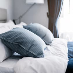 a bed with blue and white pillows and white sheets