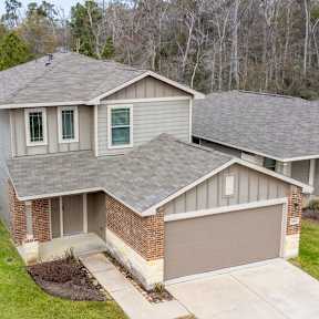 A house with a brown garage door is surrounded by other houses.