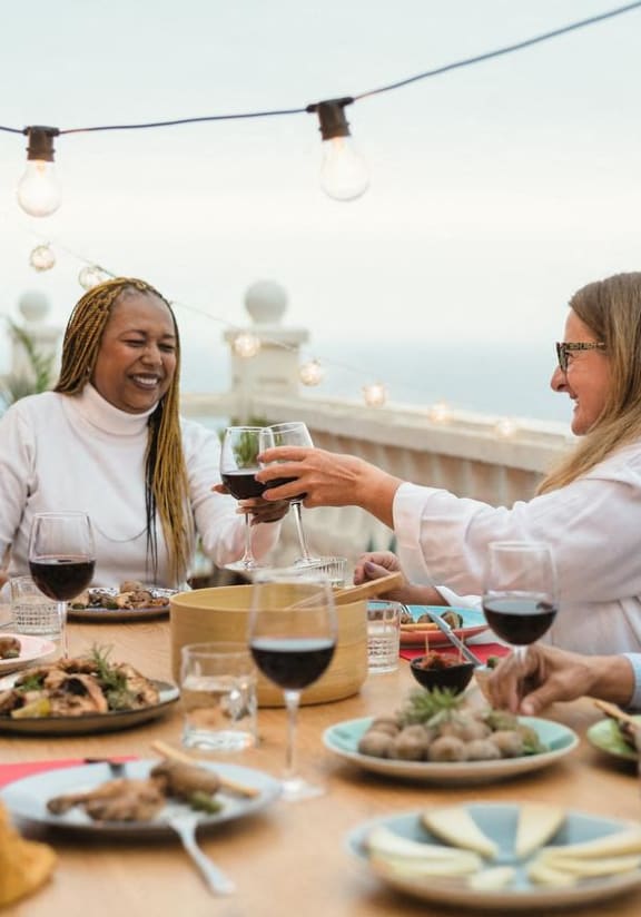 a group of people sitting around a table eating and drinking wine