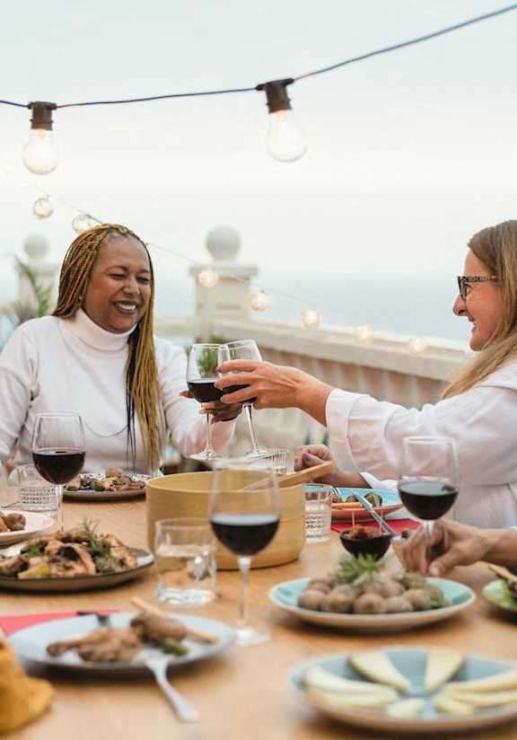 a group of people sitting around a table eating and drinking wine