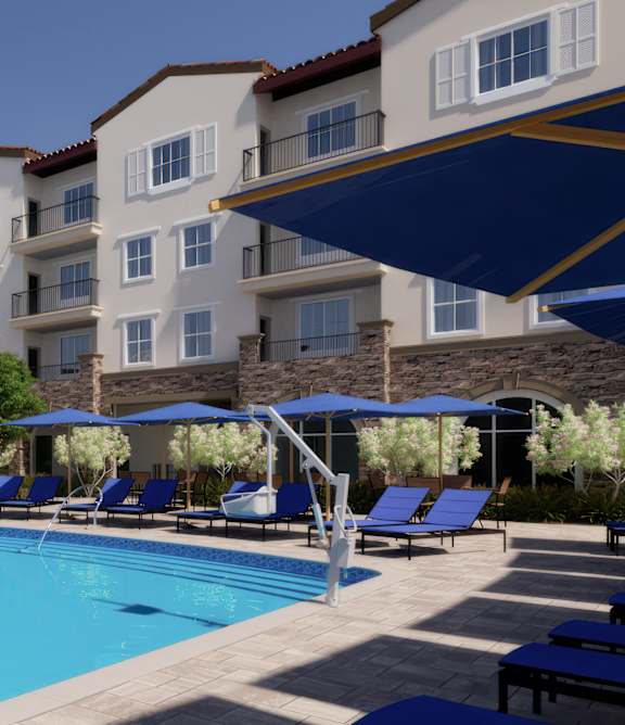 A large swimming pool is surrounded by sun loungers and apartment buildings.
