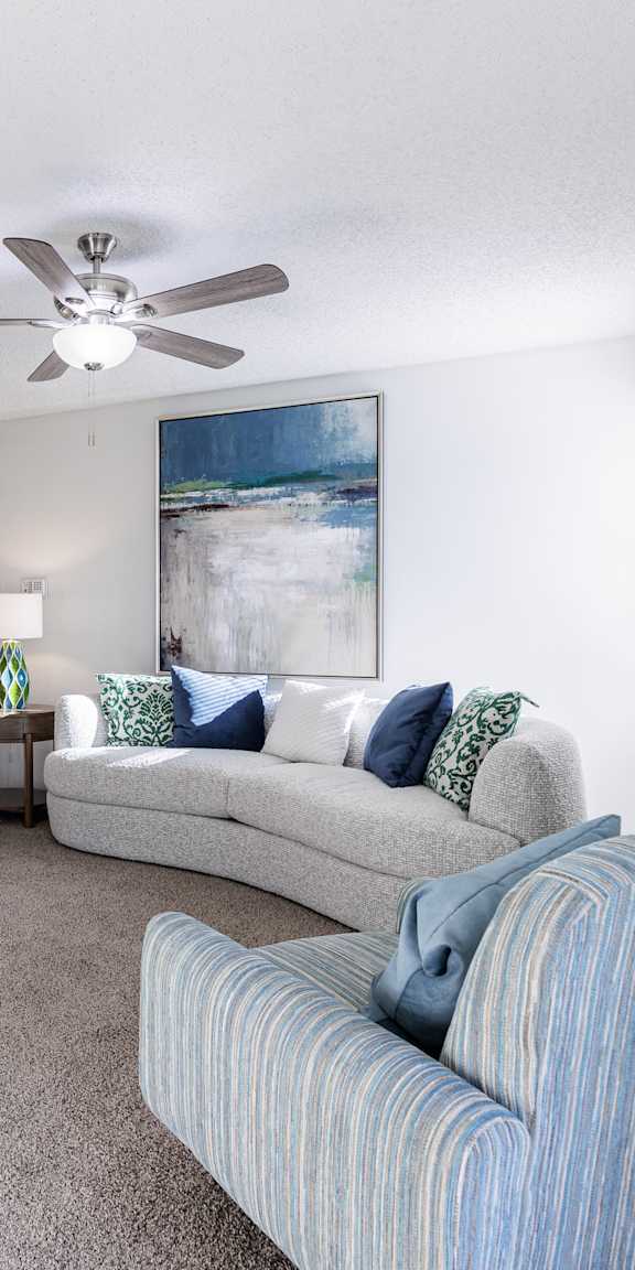 Lounge area in the model unit at Skyler Ridge Apartments, with a couch and ceiling fan.