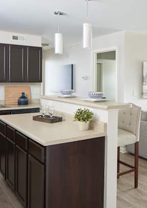 A modern kitchen with dark brown cabinets and a white island at Meadowlark Place Apartments, Iowa, 50111