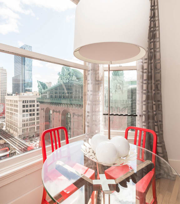 a dining room with a large window and a table with red chairs