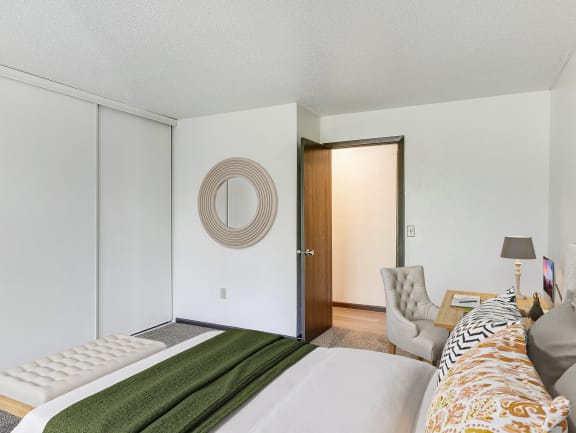 a bedroom with a bed and a chair and a door to a closet