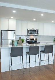 a kitchen with white cabinets and a breakfast bar with three stools
