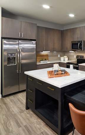 A kitchen with a black table and orange chairs.