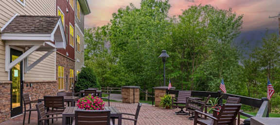 A patio with a table and chairs is surrounded by trees.