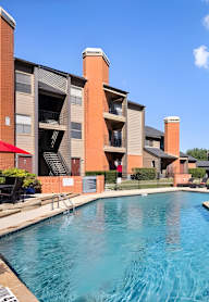 A large swimming pool in front of a multi-story apartment building.