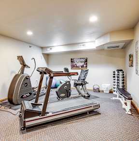 A gym room with a treadmill, exercise bike, and weights.