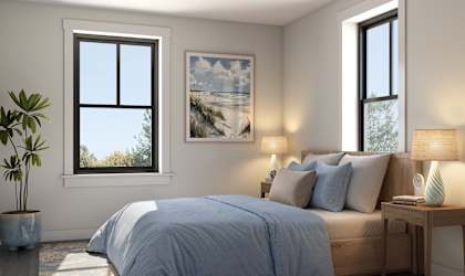 A bedroom with a bed, nightstand, and a plant.