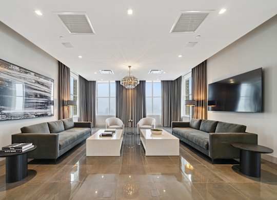 A modern living room with two dark sofas and a large painting on the wall.