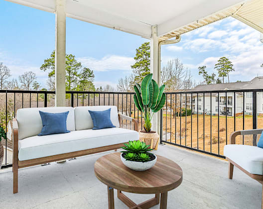 A white sofa with blue pillows sits on a wooden table on a patio.