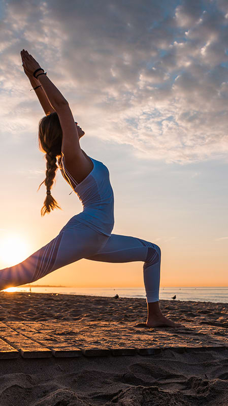 Lifestyle photo of woman doing yoga at the beach