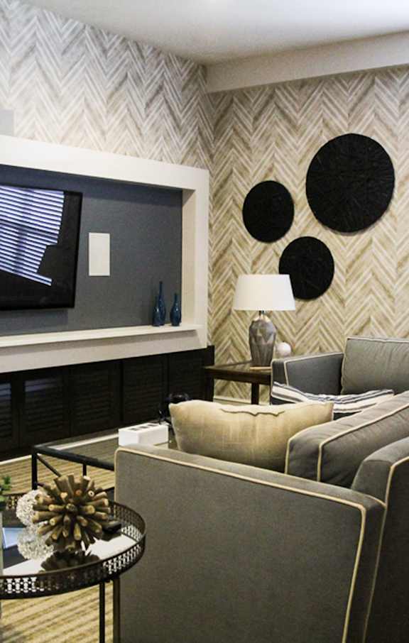 A living room with a grey couch and a black and white patterned wall.