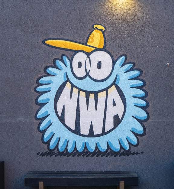a mural of a monster with a yellow hat on a blue wall