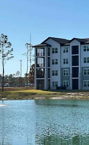 A large white building with a lake in front of it at The Beacon at 331 Apartments, Santa Rosa Beach, Florida