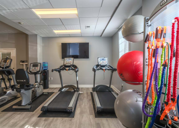 a gym with exercise machines and a tv on the wall