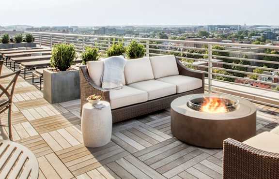 A patio with a fire pit and chairs.