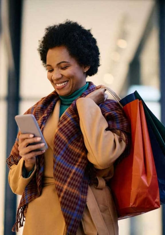 a woman looking at her cell phone while standing in a store
