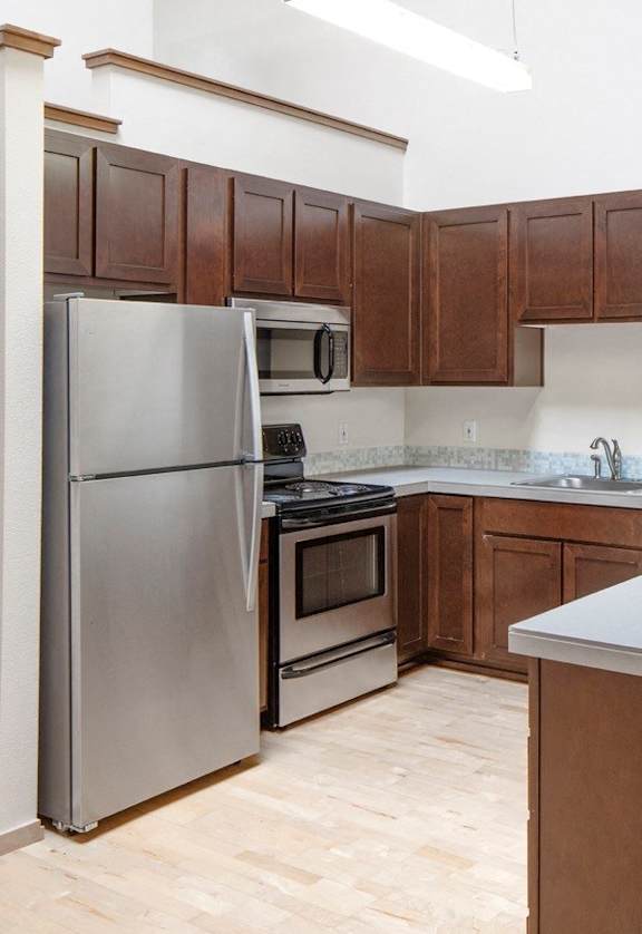 A kitchen with wooden cabinets and a stainless steel refrigerator.