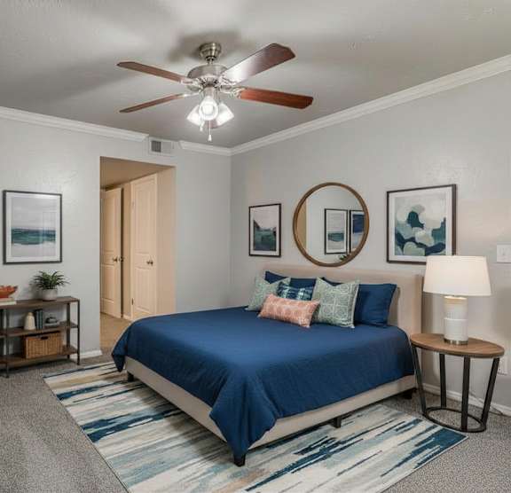 A bedroom with a blue bed and a ceiling fan.