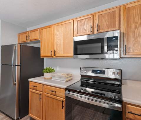 A kitchen with wooden cabinets and a black refrigerator.