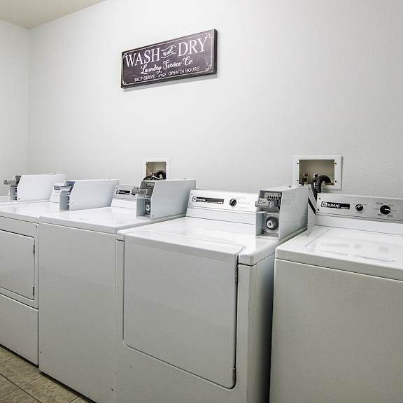 a laundry room with four washers and dryers and a sign on the wall