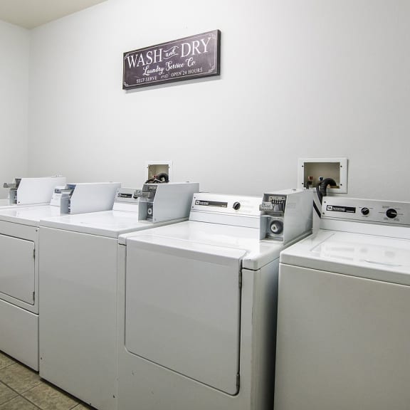 a laundry room with four washers and dryers and a sign on the wall