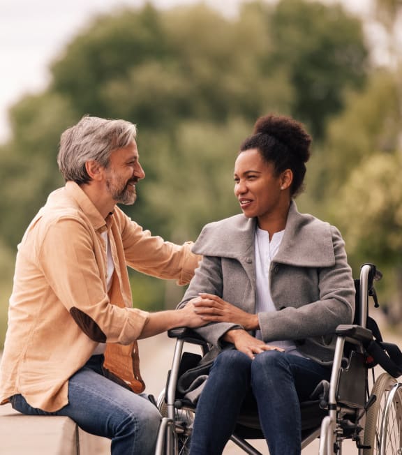 a man in a wheelchair talking to a woman in a park
