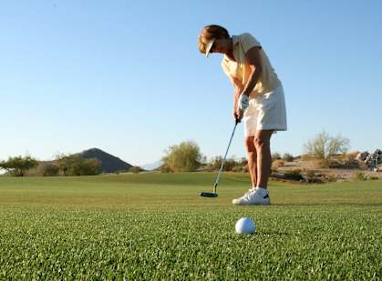 a woman hitting a golf ball on a golf course