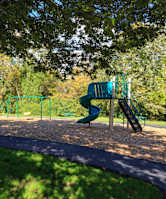 A playground with a green slide and a climbing frame.