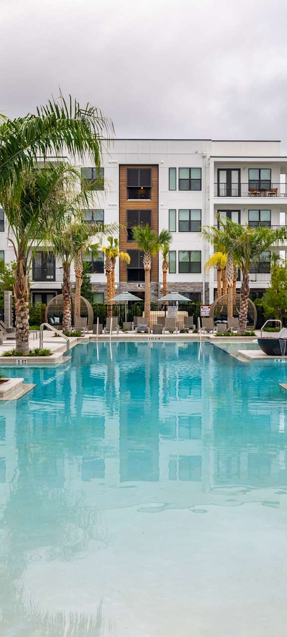 A swimming pool surrounded by palm trees and lounge chairs.