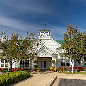 A white building with a green roof and a clock tower.
