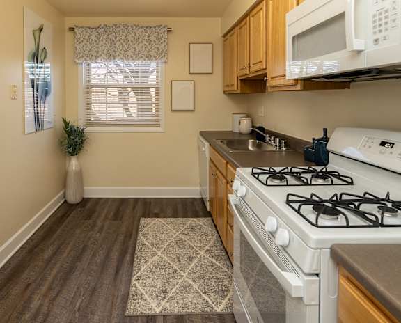 A kitchen with a white gas stove and wooden cabinets  at Liberty Gardens Apartments, Baltimore Maryland