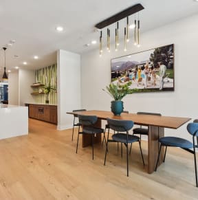 a dining area with a wooden table and chairs and a large picture on the wall
