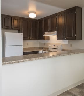 Sierra Glen apartments upgraded kitchen with white appliances and dark wood cabinets 