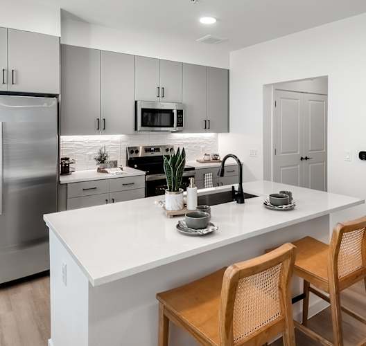 A modern kitchen with a white countertop and stainless steel appliances.