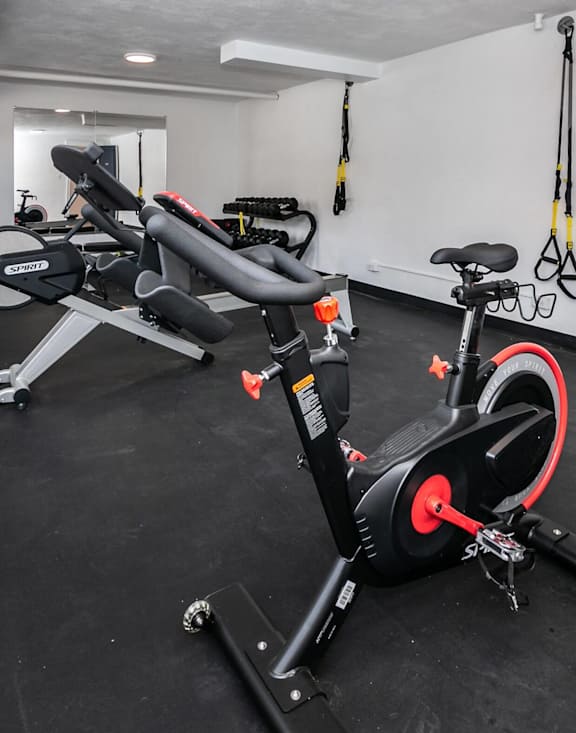 A black and red exercise bike is in a room with a black floor.