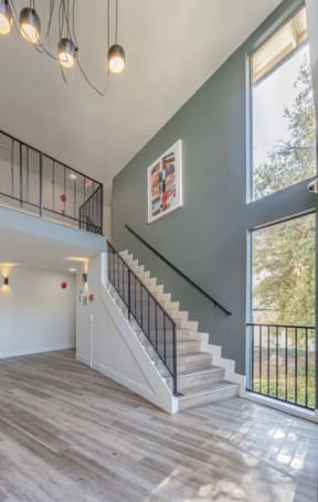 a living room with a staircase and a large window at The Hills Apartments at Thousand Oaks, California, 91360