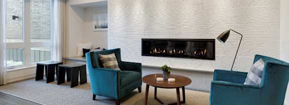A living room with a fireplace and two chairs.