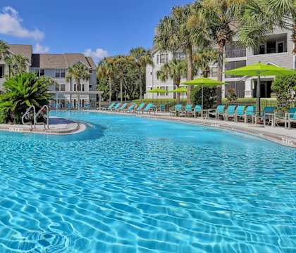 a resort style swimming pool with lounge chairs and umbrellas