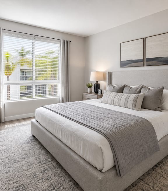 A well-lit bedroom with a large bed and a painting on the wall.